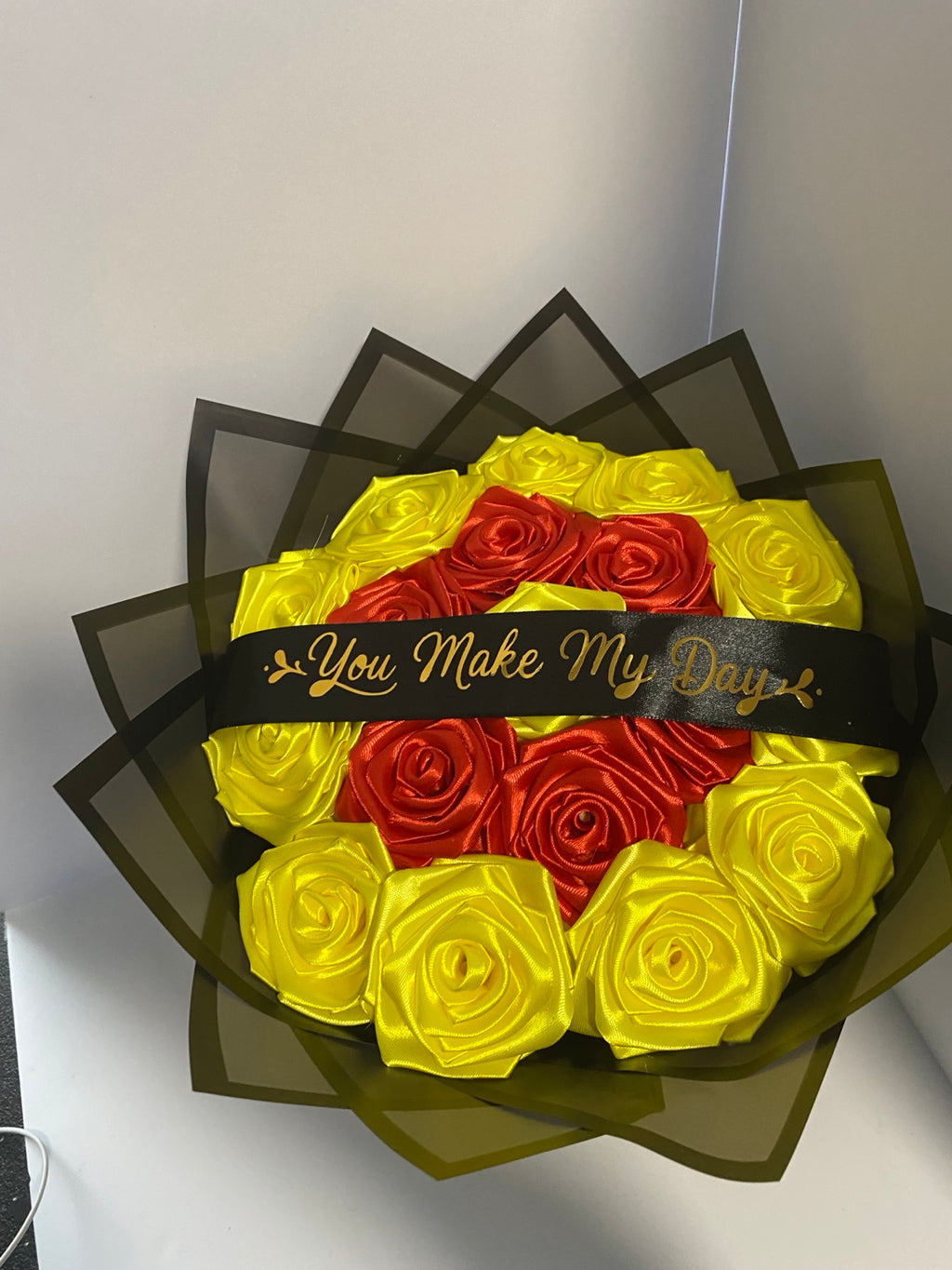 Close view of red and yellow satin ribbon roses in black wrapping