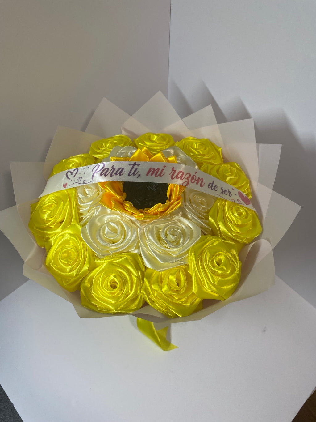 Close-up of golden yellow and ivory satin roses with sunflower center and white message ribbon