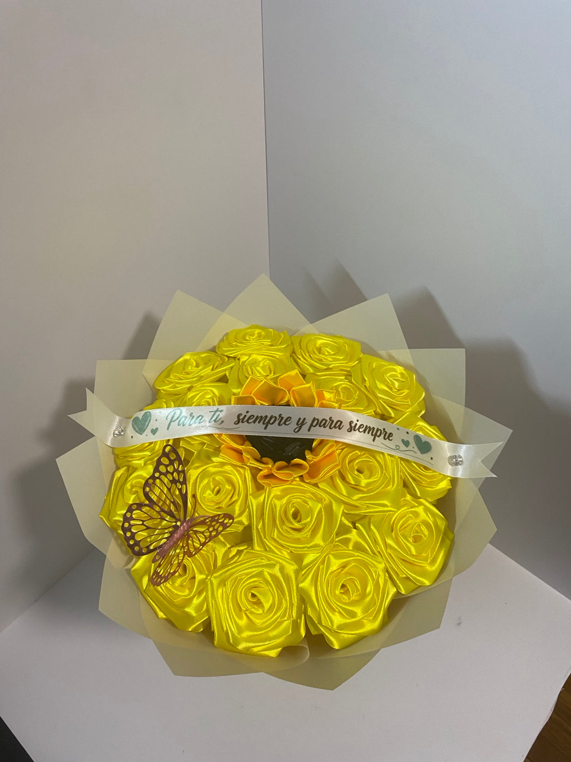 Close-up of golden satin roses, sunflower center, butterfly accent, and ivory champagne wrapping paper