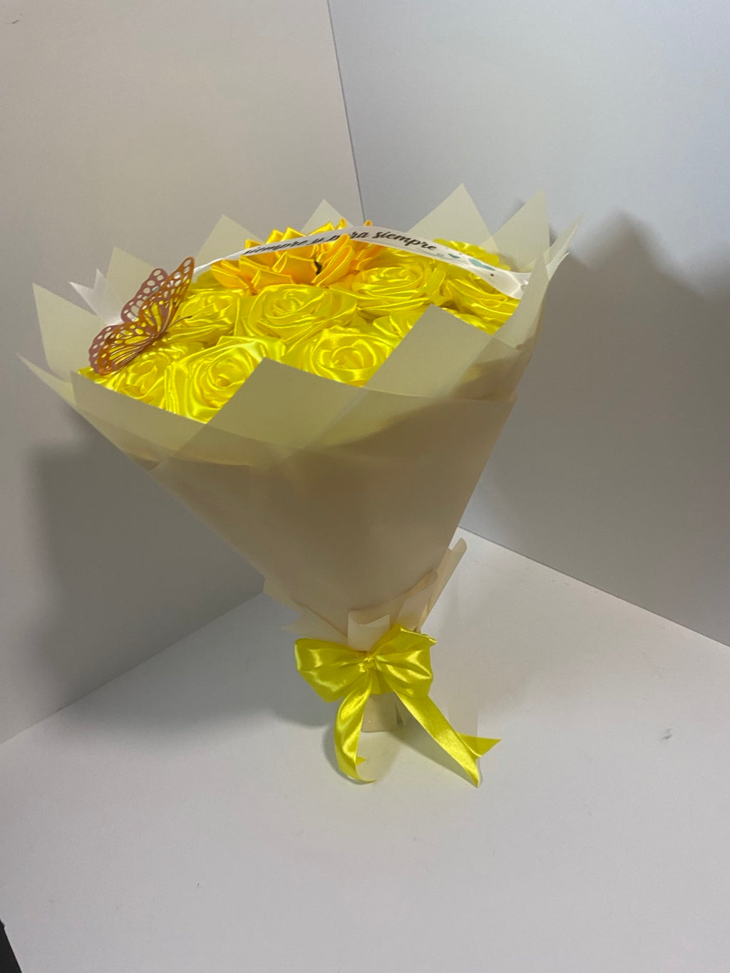 Side view of golden satin rose and sunflower bouquet wrapped in ivory champagne paper