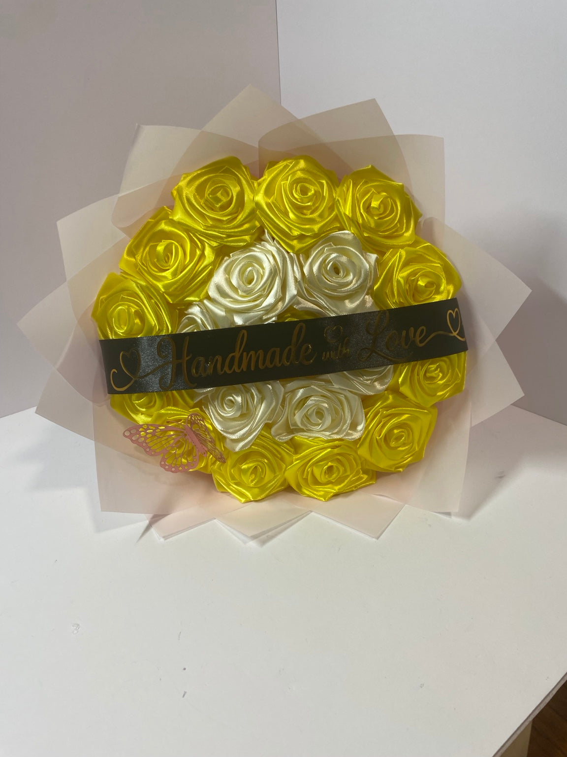 Golden yellow and ivory satin rose bouquet with pink butterfly, black Handmade with Love ribbon, and blush wrapping paper