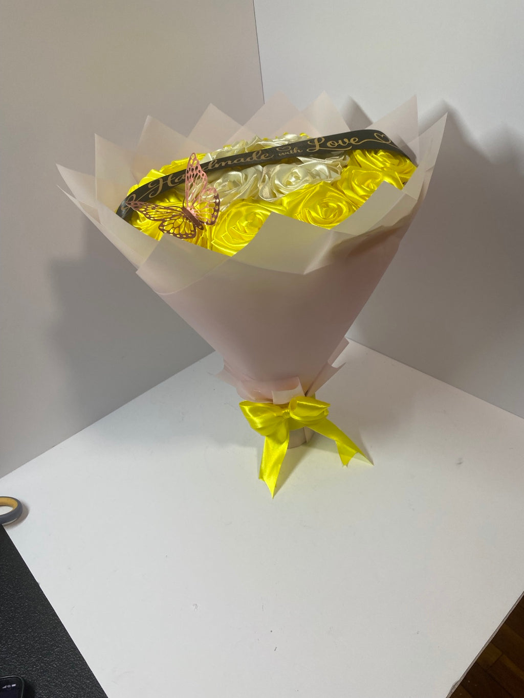 Full side view of golden yellow and ivory satin rose bouquet in soft blush wrapping paper