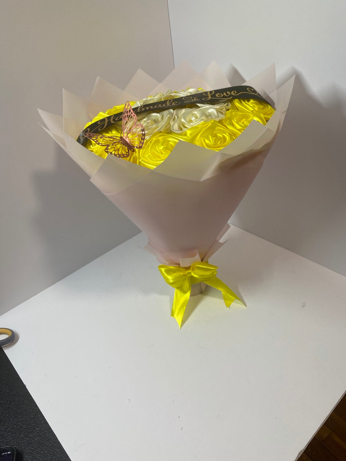 Full side view of golden yellow and ivory satin rose bouquet in soft blush wrapping paper