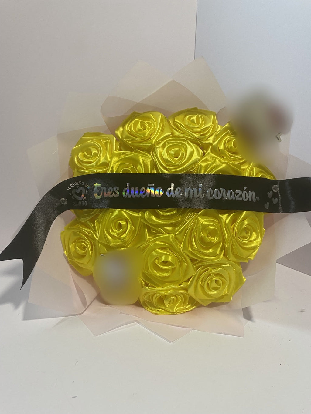 Front view of golden yellow satin rose bouquet with blurred character accents and soft blush wrapping paper