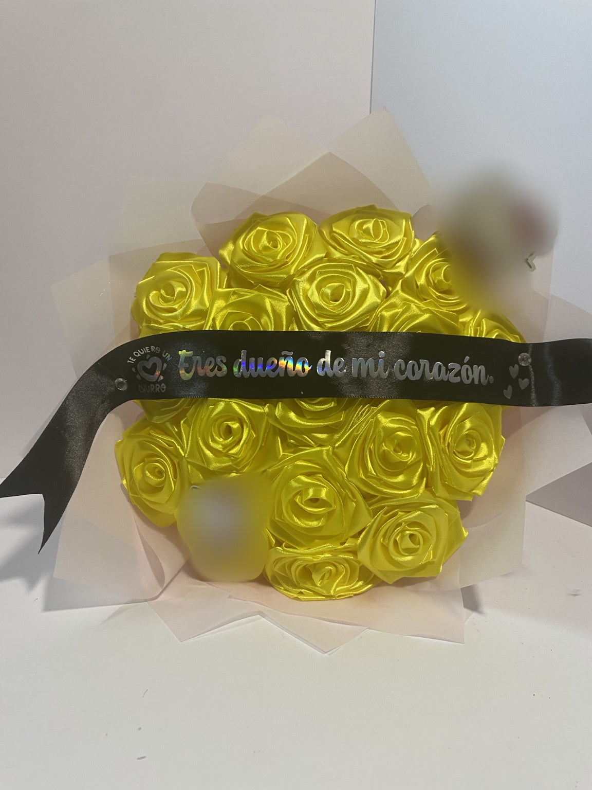 Front view of golden yellow satin rose bouquet with blurred character accents and soft blush wrapping paper