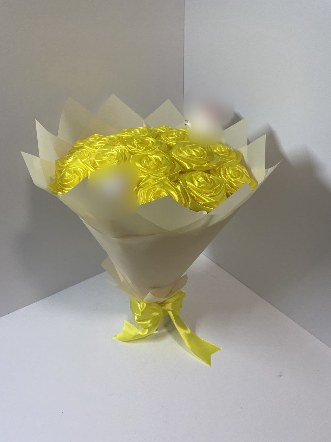 Full side view of golden yellow satin rose bouquet with blurred character accents and blush champagne wrapping paper