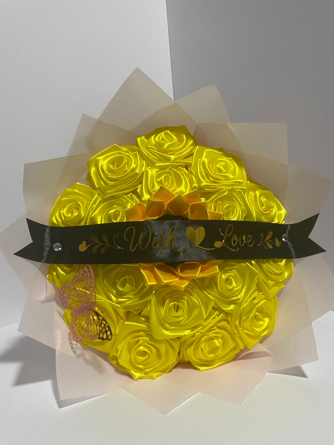 Close-up of golden satin roses with sunflower center, butterfly, and black With Love message ribbon