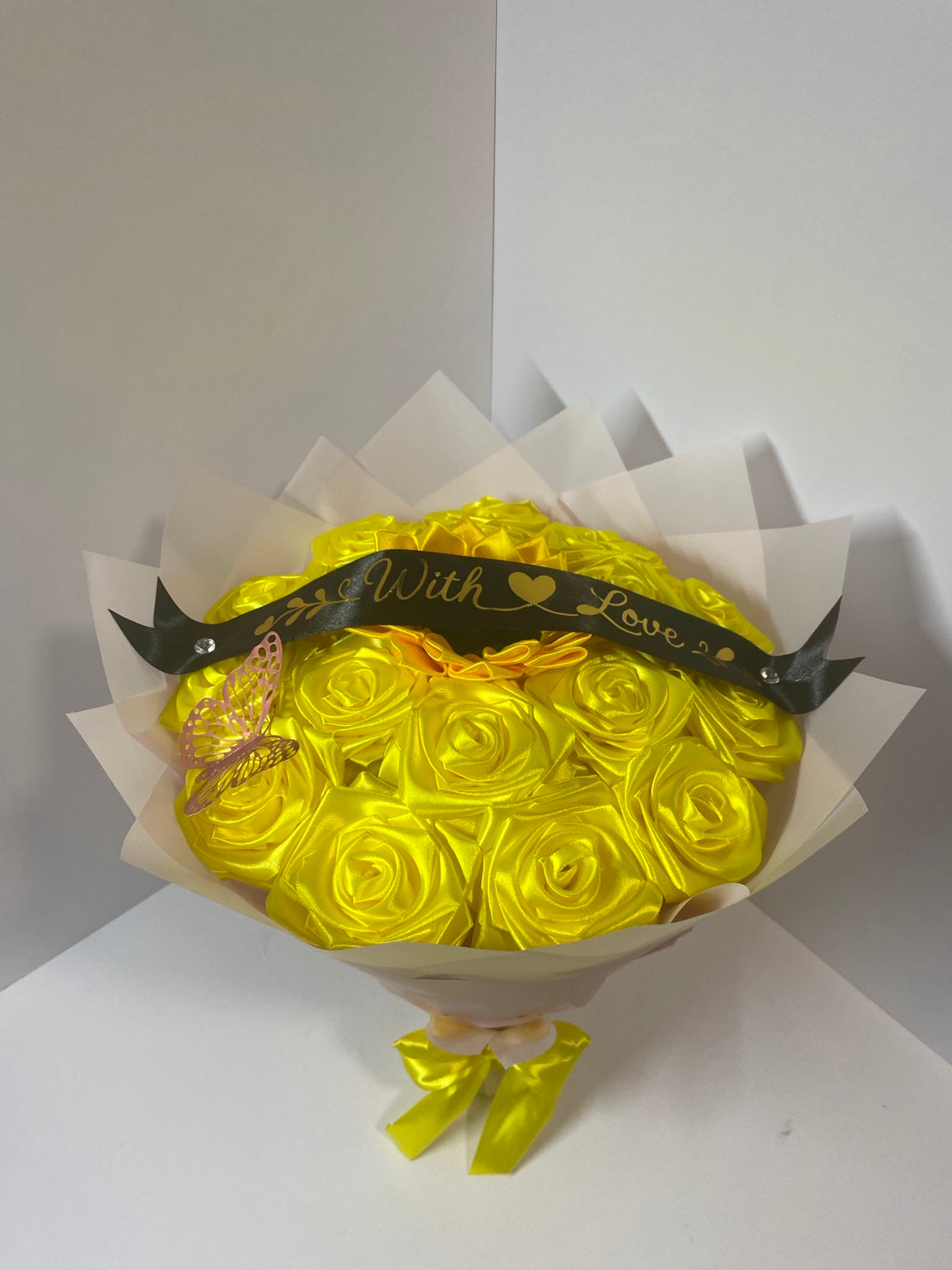 Golden satin rose bouquet with sunflower center, pink butterfly, black With Love ribbon, and soft blush wrapping paper