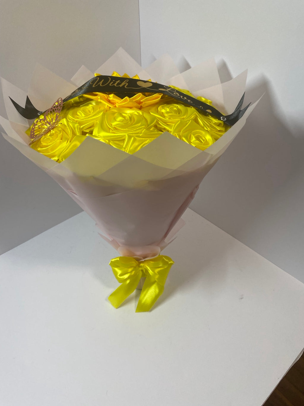 Full side view of golden satin rose and sunflower bouquet with soft blush wrapping paper