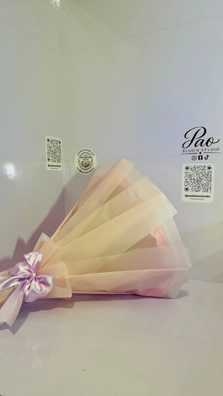Side profile of pink wrapped satin rose bouquet with lavender bow