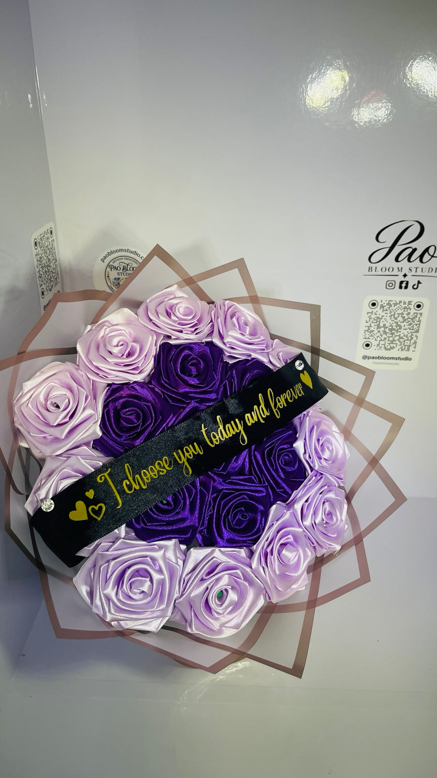 Close-up of purple and light lavender satin roses with custom message ribbon